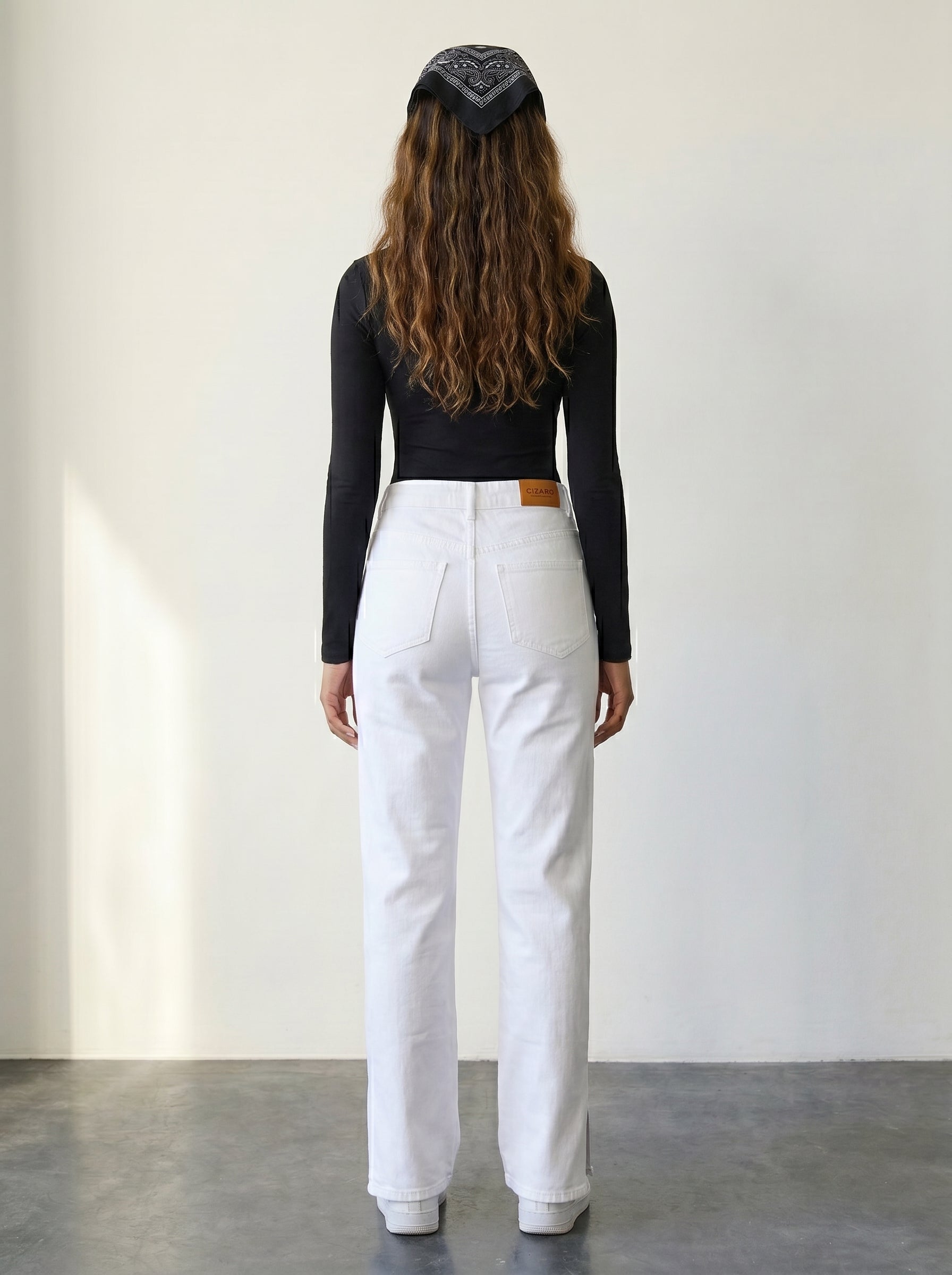 High-waisted white straight-leg jeans with a crisscross belt.